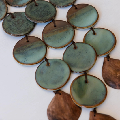 Collection of green and brown ceramic discs on a white background