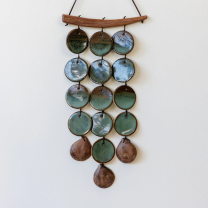 Decorative hanging with green and brown circular elements on a white background