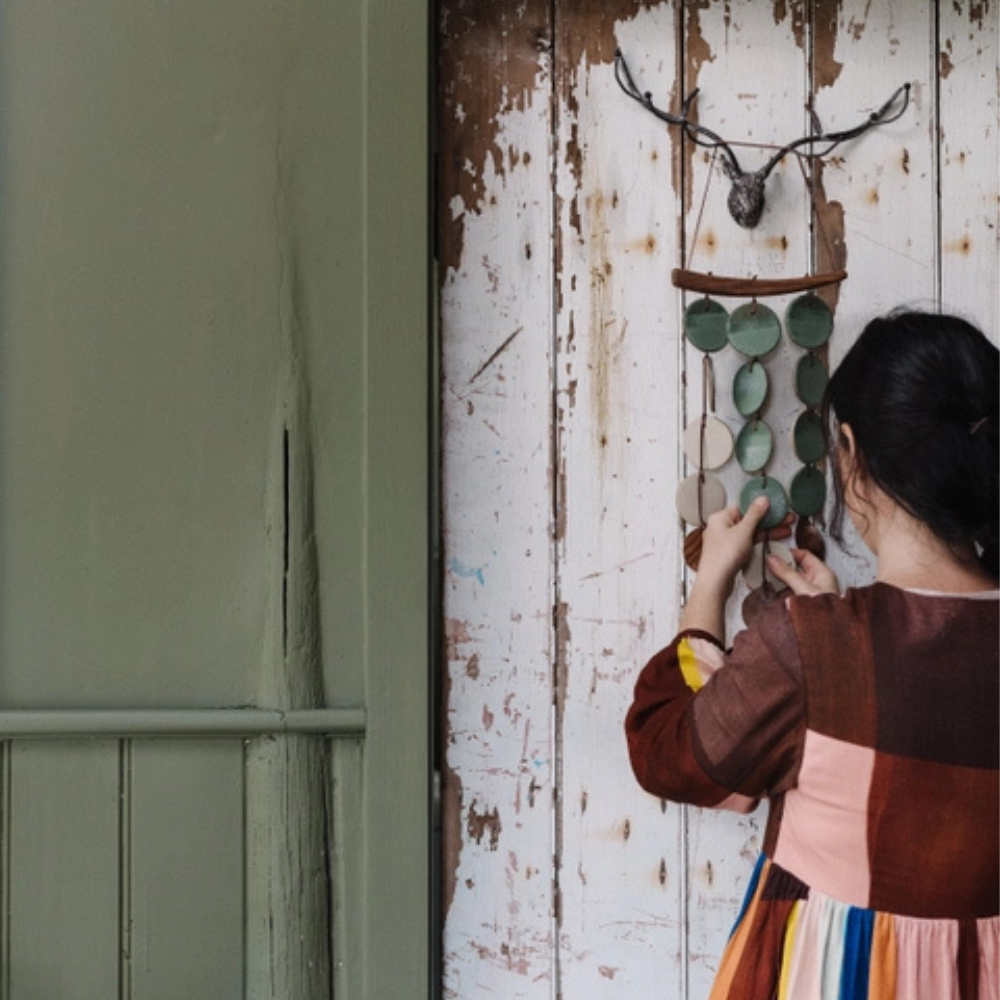 Person adjusting a wall hanging with a deer head mount on a rustic wooden wall.