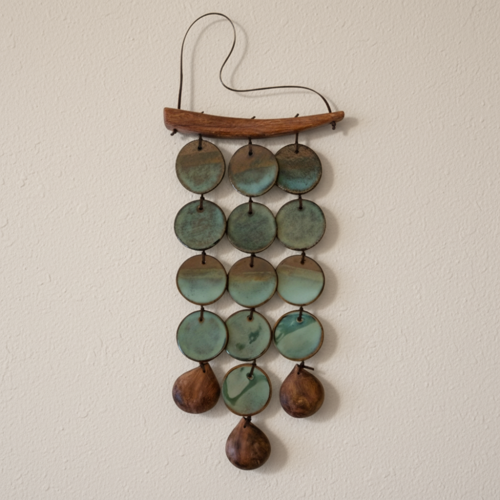 Decorative wall hanging with green and brown ceramic and wood circles on a beige background