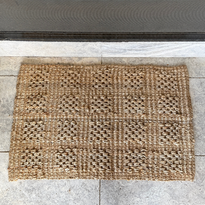 Textured doormat with geometric pattern on a concrete floor