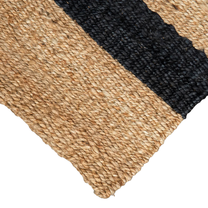 Close-up of a woven mat with black and beige stripes on a white background