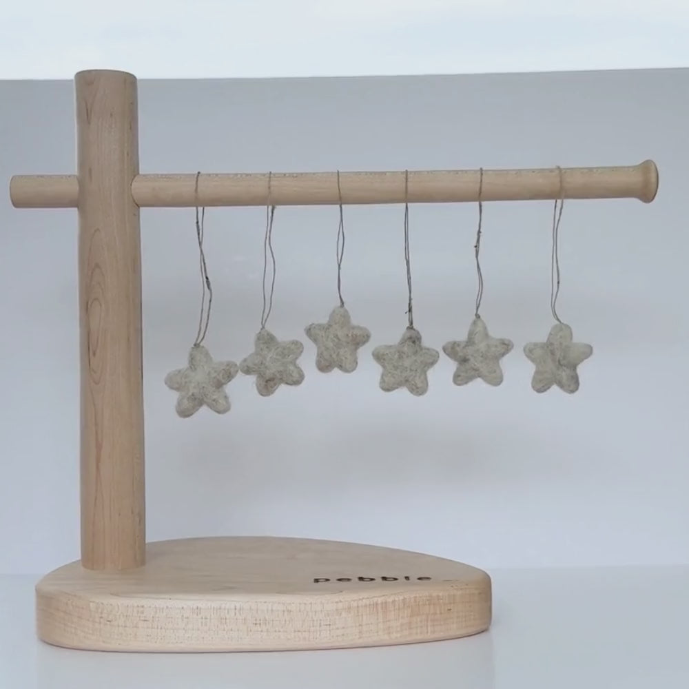 Six tiny felt star decorations hanging from a wooden stand