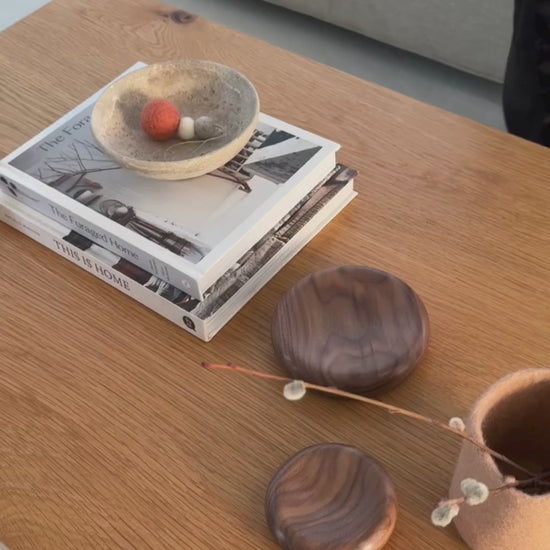 Hand-felted wool hanging diffuser sitting in a stone bowl on a styled coffee table.