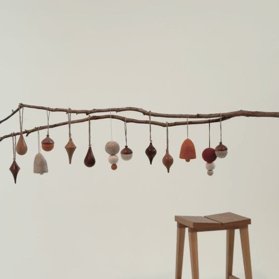 Pebble Studios Christmas decorations hanging from a branch against a plain background